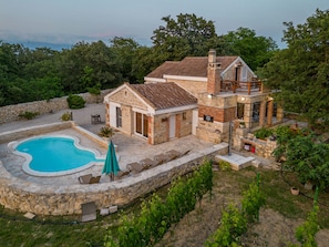 A stone house with a swimming pool and outdoor seating.