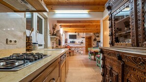 Une cuisine équipée d’une cuisinière, de meubles en bois, d’un mur en pierre et d’une grande armoire en bois ornée de sculptures.