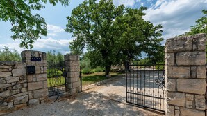Une entrée fermée par un portail, avec des murs en pierre et un portail en métal.