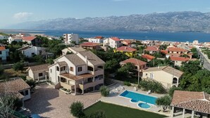 Un barrio residencial con una casa grande que cuenta con piscina y vistas al mar y a las montañas.