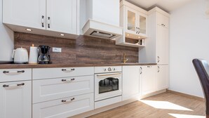 A modern kitchen with white cabinetry, a built-in oven, and a wooden countertop. - Villa Ivo (Posedarje)