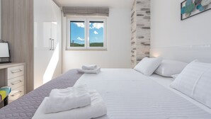 A bedroom with a bed, a desk, a window with a view, and a wall-mounted artwork. - Villa Ivo (Posedarje)