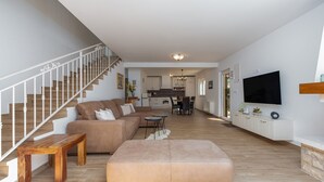 A spacious living area with a staircase, a sofa, a coffee table, and a TV mounted on the wall. - Villa Ivo (Posedarje)