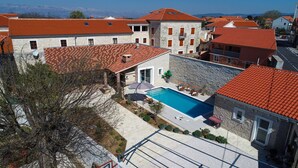 Zona residencial con edificios de piedra, piscina y vistas a las montañas.