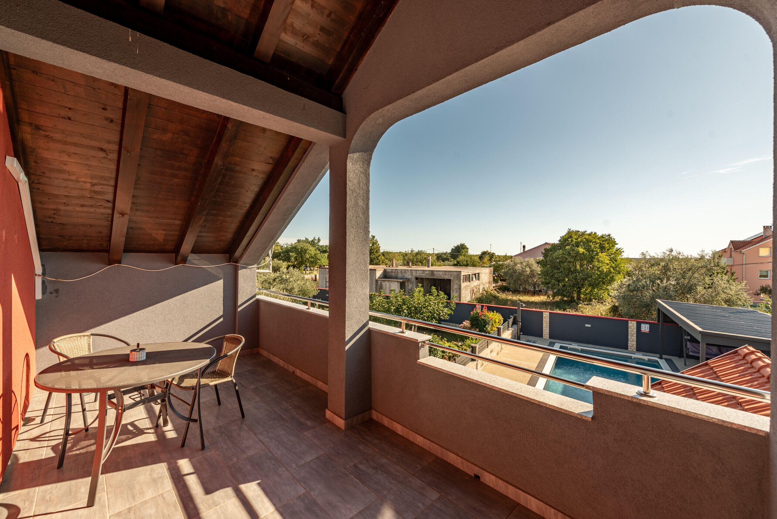 Un balcon avec une table et des chaises, une piscine et une vue sur les bâtiments environnants.