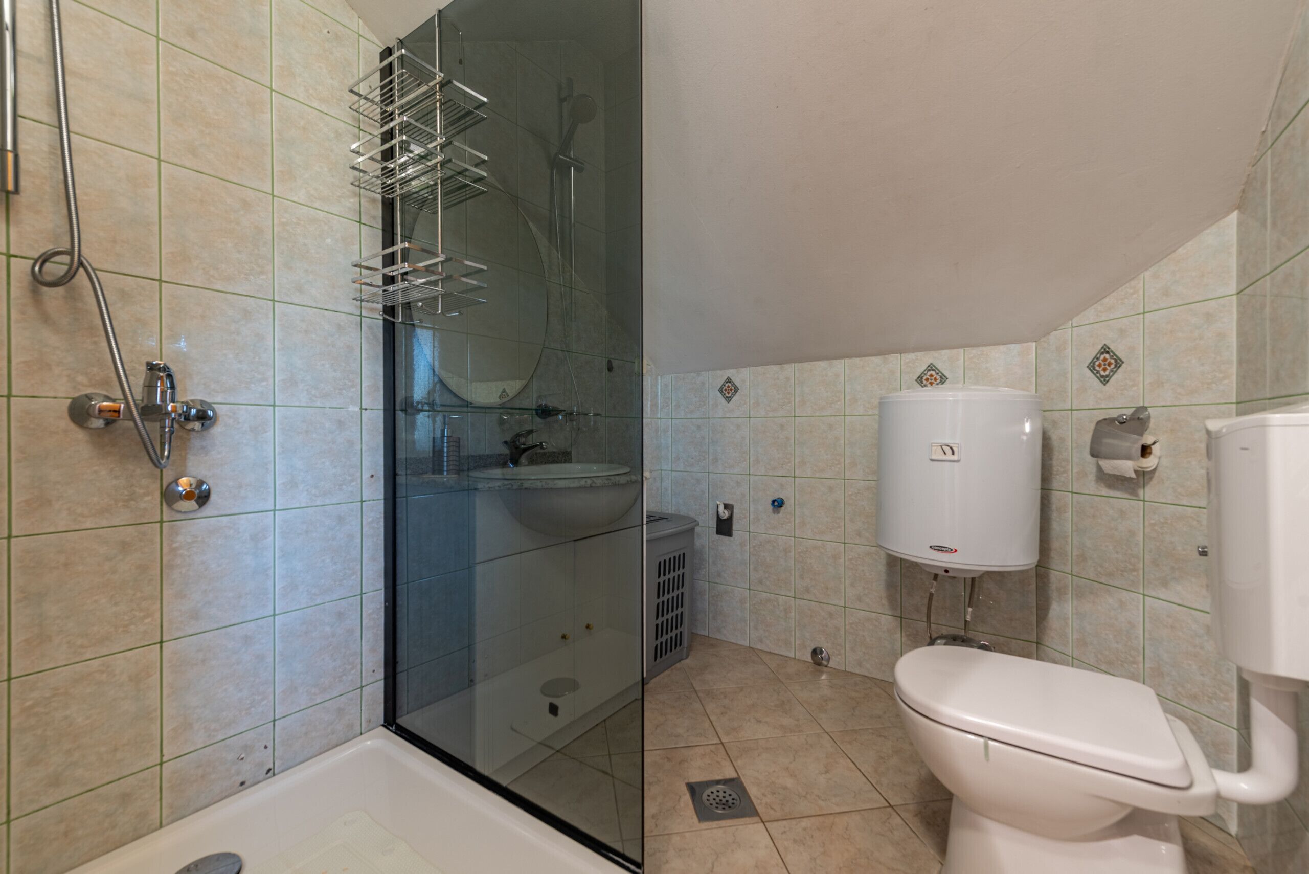 A bathroom with a glass-enclosed shower, a toilet, and a sink.