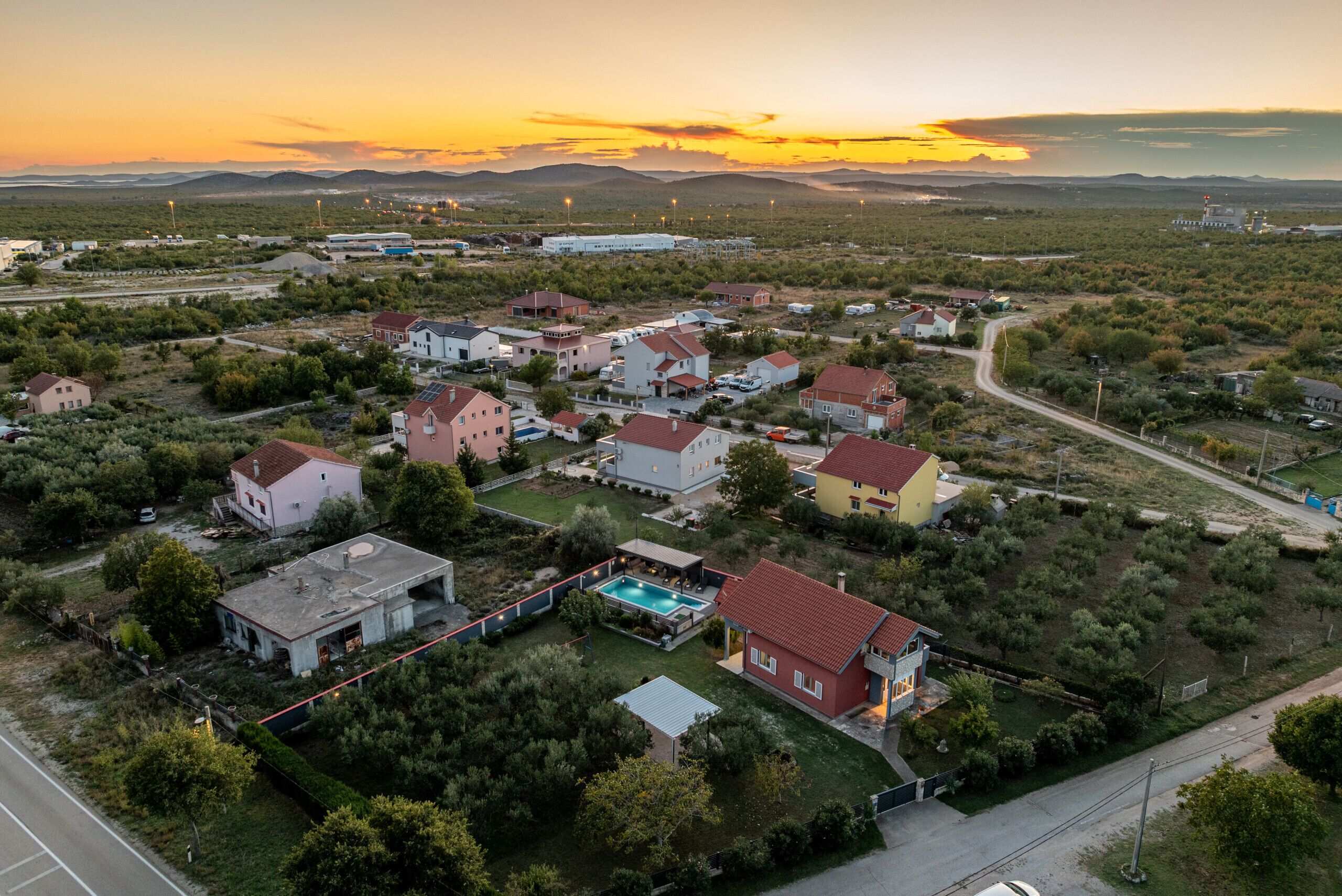 Vue aérienne d’un quartier résidentiel avec des maisons, une piscine et une route.