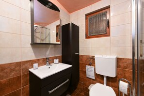 Ein Badezimmer mit einem weißen Waschbecken, einem schwarzen Schrank und einer Toilette.
