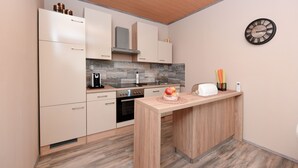 Una cocina moderna con armarios de madera, horno empotrado e isla de madera con fruta.