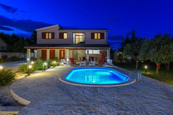 Ein zweistöckiges Haus mit Pool und Sitzbereich im Freien.