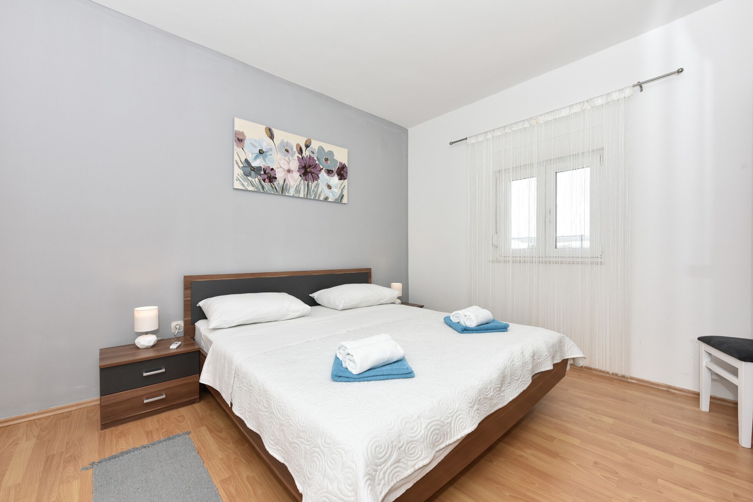 Un dormitorio moderno con una cama grande, una mesita de noche, una silla y una ventana con cortinas.