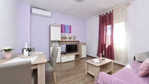 A modern room with a wooden desk, a bed, a TV, and a small table. - Villa Nea (Posedarje)