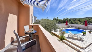 A balcony with a table, chairs, a pool, and umbrellas. - Villa Nea (Posedarje)