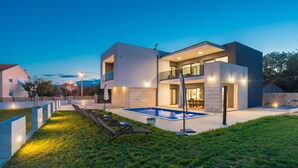 A modern two-story house with a swimming pool, outdoor seating, and a well-lit patio area. - Villa F&A (Sveti Filip i Jakov)