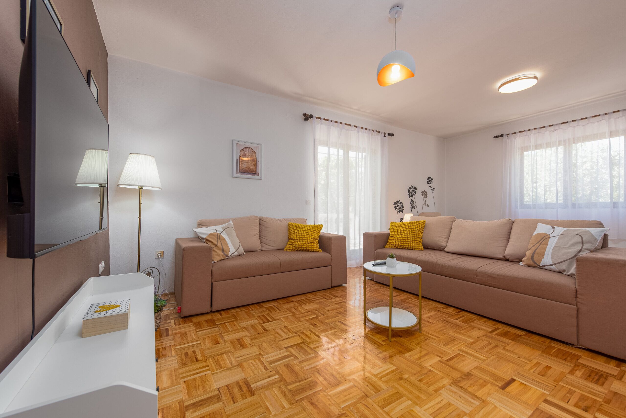 Una sala moderna con dos sofás, una mesa de centro, un televisor y un espejo.