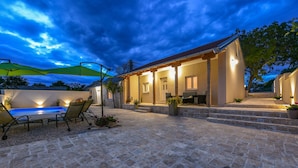 Eine Terrasse mit Pool, Sitzgelegenheiten im Freien und einer überdachten Veranda.