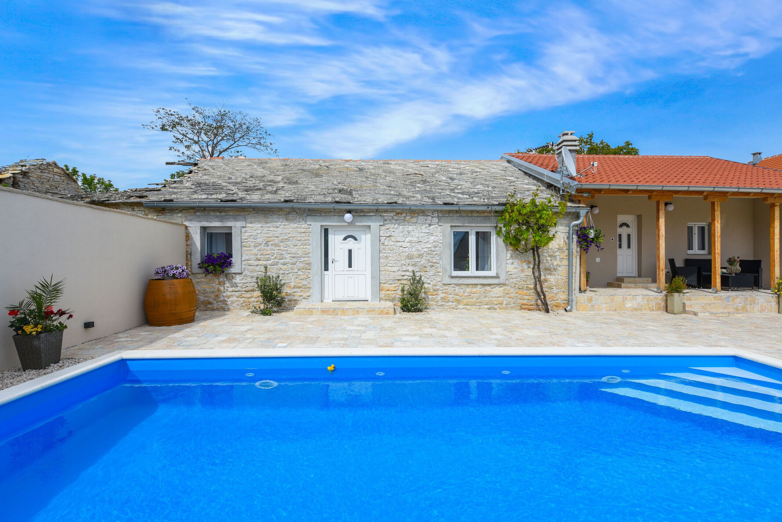 A stone house with a swimming pool in front.