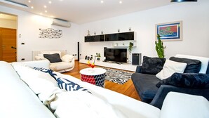 A modern living room with a sofa, a coffee table, and a TV. - Villa Sky (Rovinj)