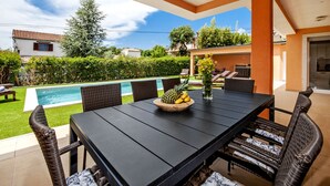 An outdoor patio with a pool, dining table, and chairs. - Villa Sky (Rovinj)