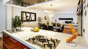 A modern kitchen with a central island, stainless steel appliances, and a dining area in the background. - Villa Sky (Rovinj)