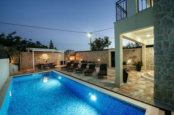 A swimming pool with lounge chairs, stone walls, and a stone building with a balcony. - Villa Castelo Coza (Posedarje)