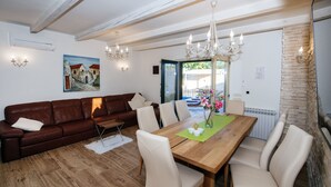 En matplats med ett träbord, beige stolar, en brun lädersoffa och en kristallkrona.