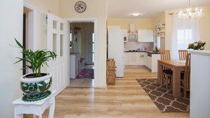Una cocina moderna con armarios blancos, una mesa de comedor de madera y una lámpara de araña.