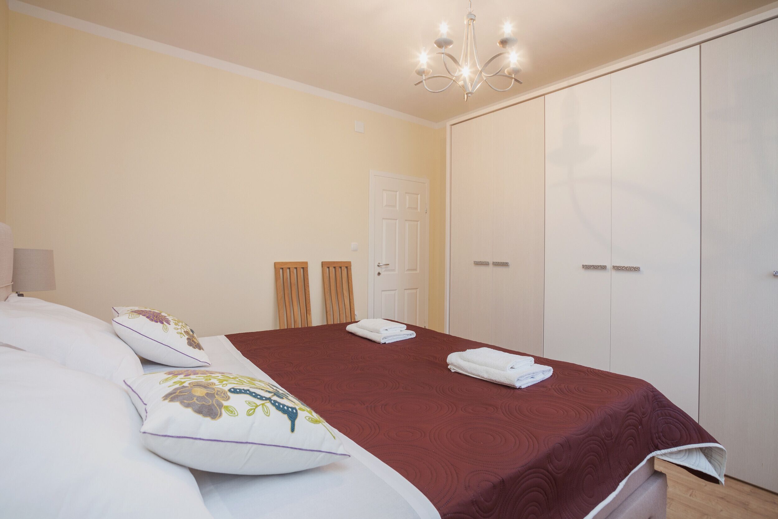 A bedroom with a bed, a wardrobe, and a chandelier.