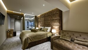 A modern bedroom with a large bed, a sofa, and a TV on the wall. - Villa Lavie (Zadar)