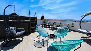 A rooftop terrace with a hanging chair, two blue chairs, and a table with a bowl of fruit. - Villa Lavie (Zadar)