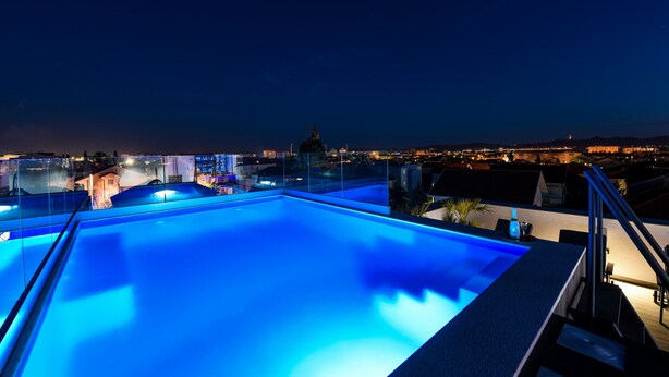 A rooftop infinity pool with a clear view of the city skyline at night. - Villa Lavie (Zadar)