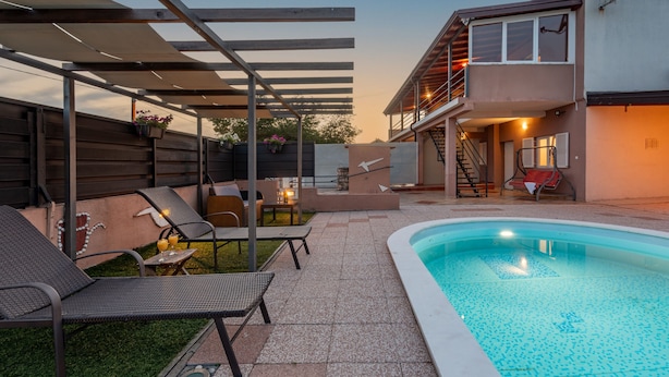 A backyard with a swimming pool, outdoor seating, and a covered patio area. - Villa Dandelion (Benkovac)