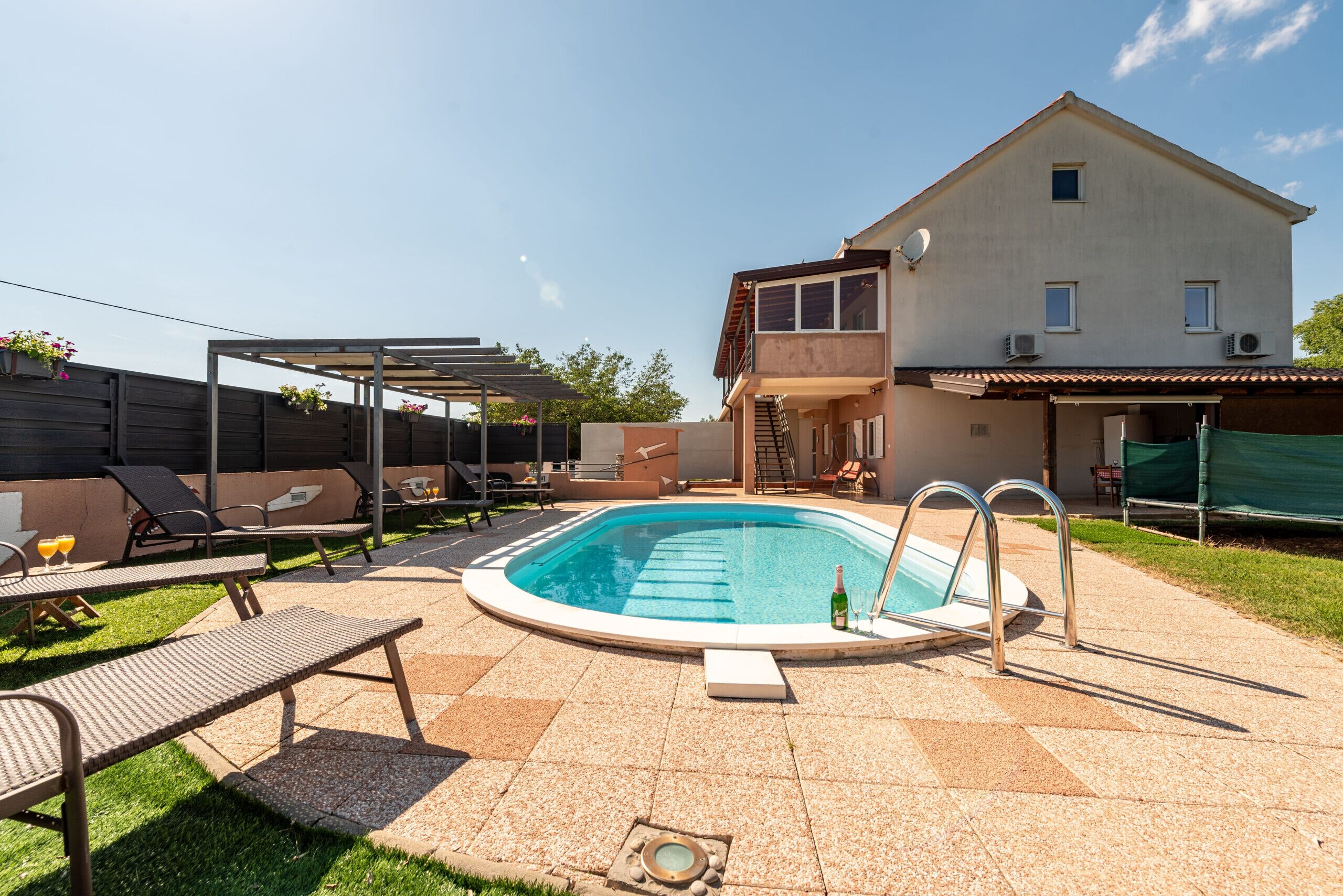 A swimming pool with lounge chairs and a covered seating area.