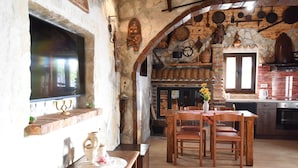 Eine rustikale Küche mit Steinwand, Holzmöbeln und Fliesenboden.
