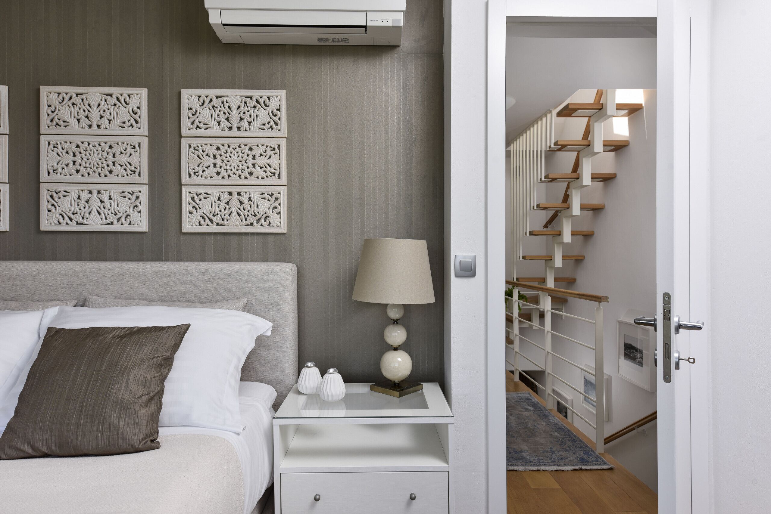 Une chambre moderne comprenant un lit, une table de chevet, une lampe, des panneaux muraux décoratifs et un escalier.
