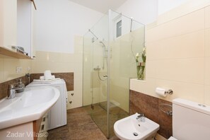 Un baño moderno con cabina de ducha de vidrio, lavamanos y un bidé.