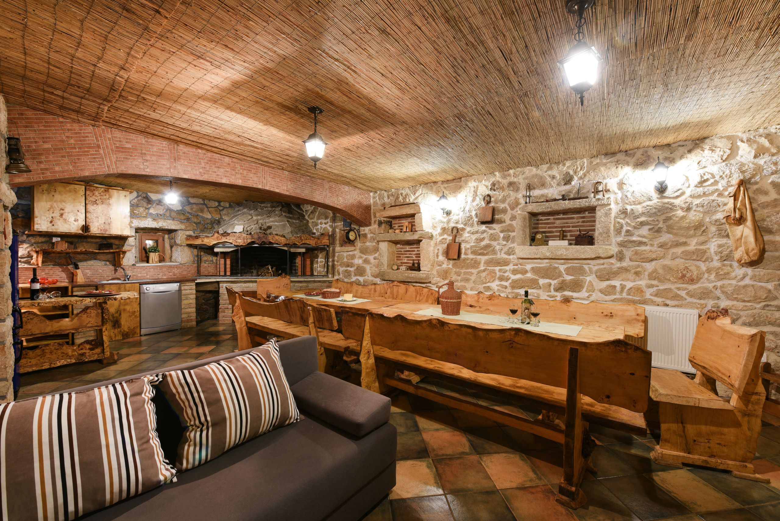 A rustic interior with a stone wall, wooden furniture, and a fireplace.