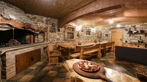 A rustic dining area with stone walls, wooden furniture, and a stone fireplace. - Villa Smilje (Posedarje)