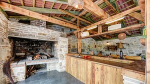 A rustic kitchen with a stone fireplace, wooden beams, and a bar area. - Villa Smilje (Posedarje)