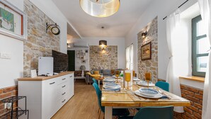 Cozinha moderna com parede de pedra, área de refeições com cadeiras azuis e mesa de madeira posta para quatro.