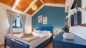 Quarto com cama azul, teto de madeira e janela com cortinas.
