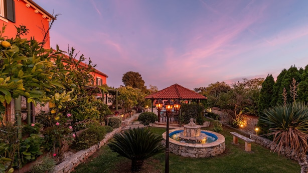 A garden with a gazebo, a fountain, and a stone wall. - Villa Stocco (Preko)