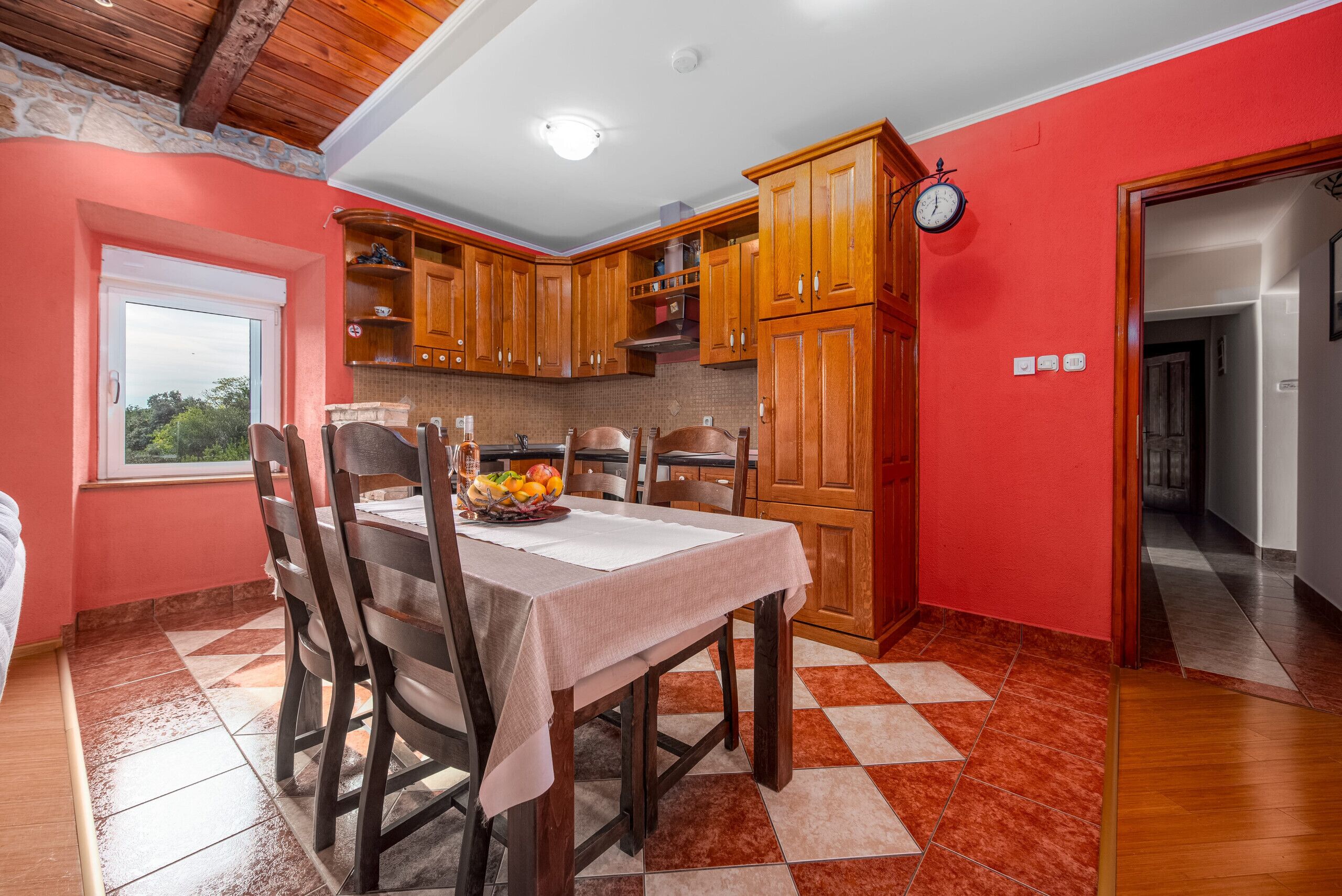 Una cocina con armarios de madera, una mesa de comedor con sillas y un frutero.