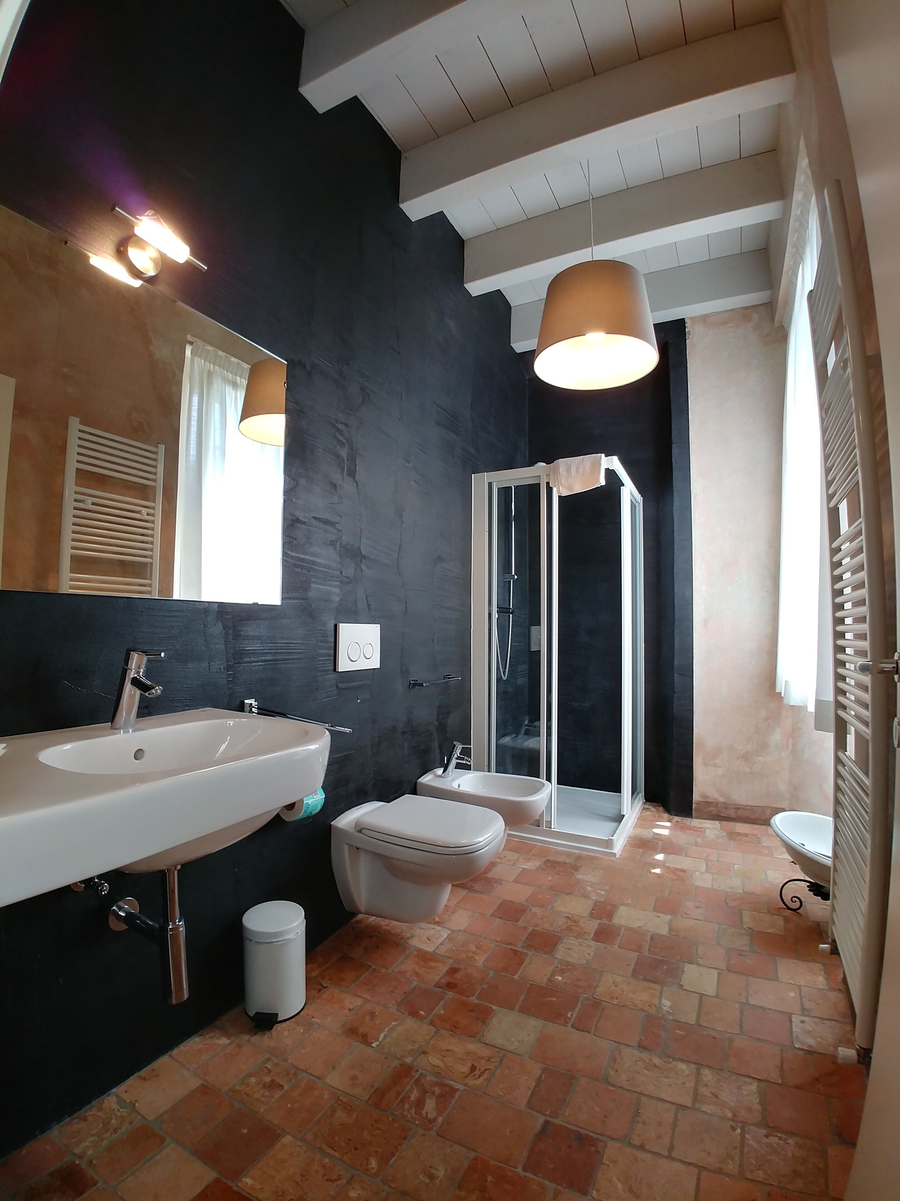 A modern bathroom with a large sink, two toilets, a shower, and a tiled floor.