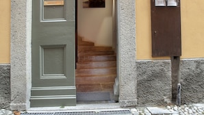 A building entrance with a green door, a stone staircase, and a mailbox. - Balbianino (Tremezzina)