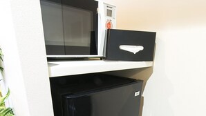 A compact kitchen with a black refrigerator, a microwave, and a small drawer unit. - Mina Aoi Apartment (Nagoya)