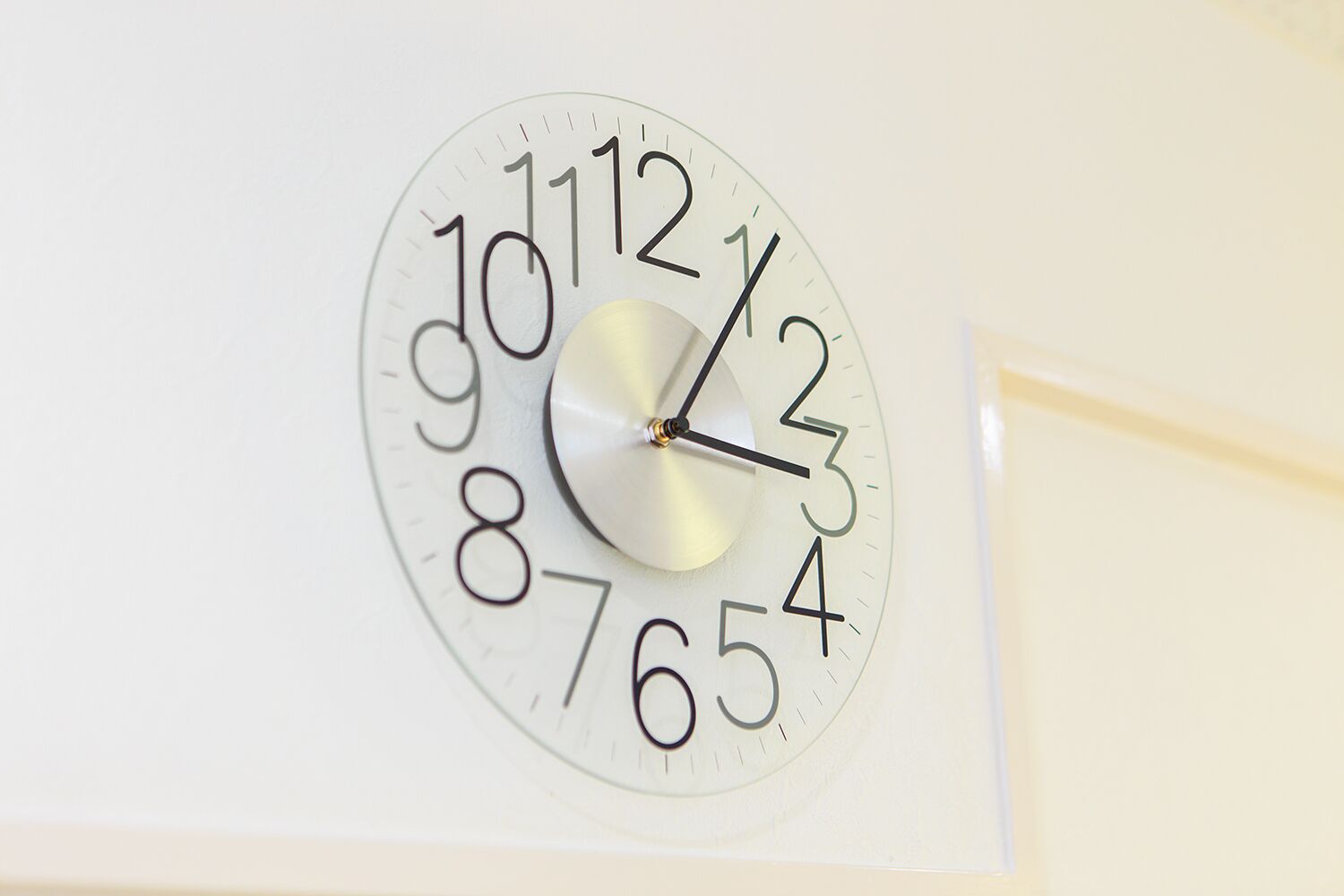 A wall clock with a white face and black numbers.