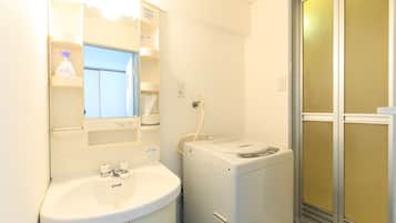 A compact bathroom with a sink, mirror, and a compact washer-dryer unit.