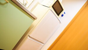 Een compacte koelkast met een digitaal display en bedieningspaneel, geplaatst in een hoek van een kamer met groene wanden en houten vloeren.