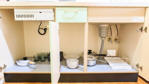 Een keuken met een spoelbak, een kookplaat en diverse keukengerei.
